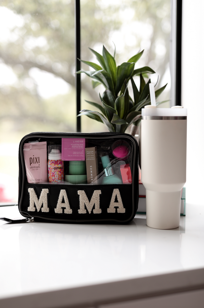 Black cosmetic bag with 'MAMA' lettering, filled with skincare products, on a white surface.