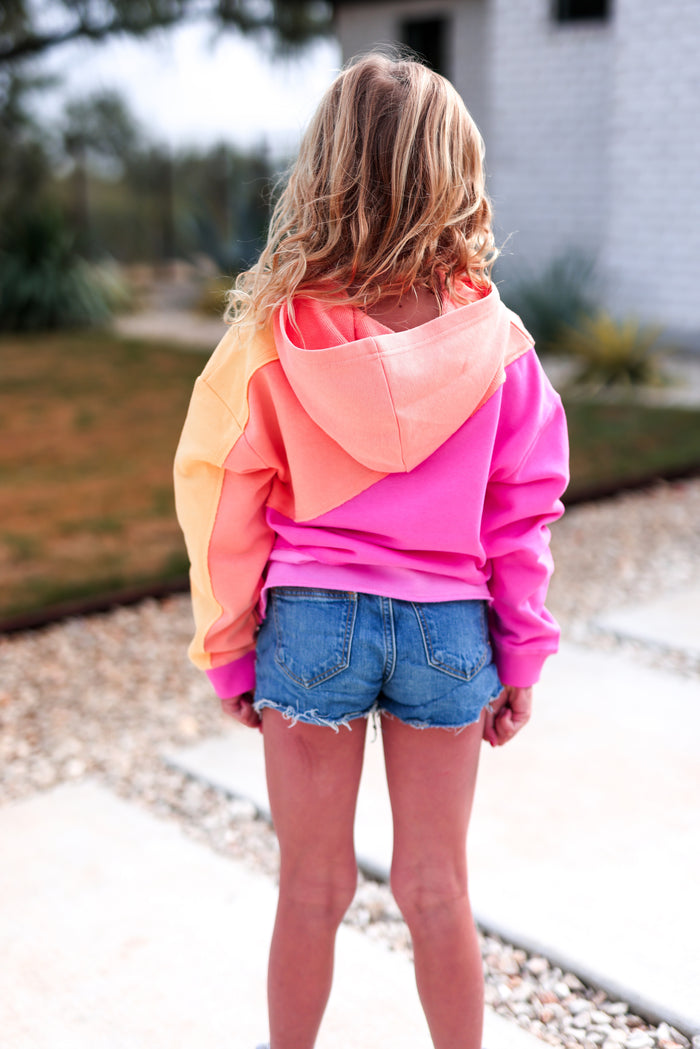 Colorful gradient hoodie in pink and orange, perfect for casual wear, paired with denim shorts.