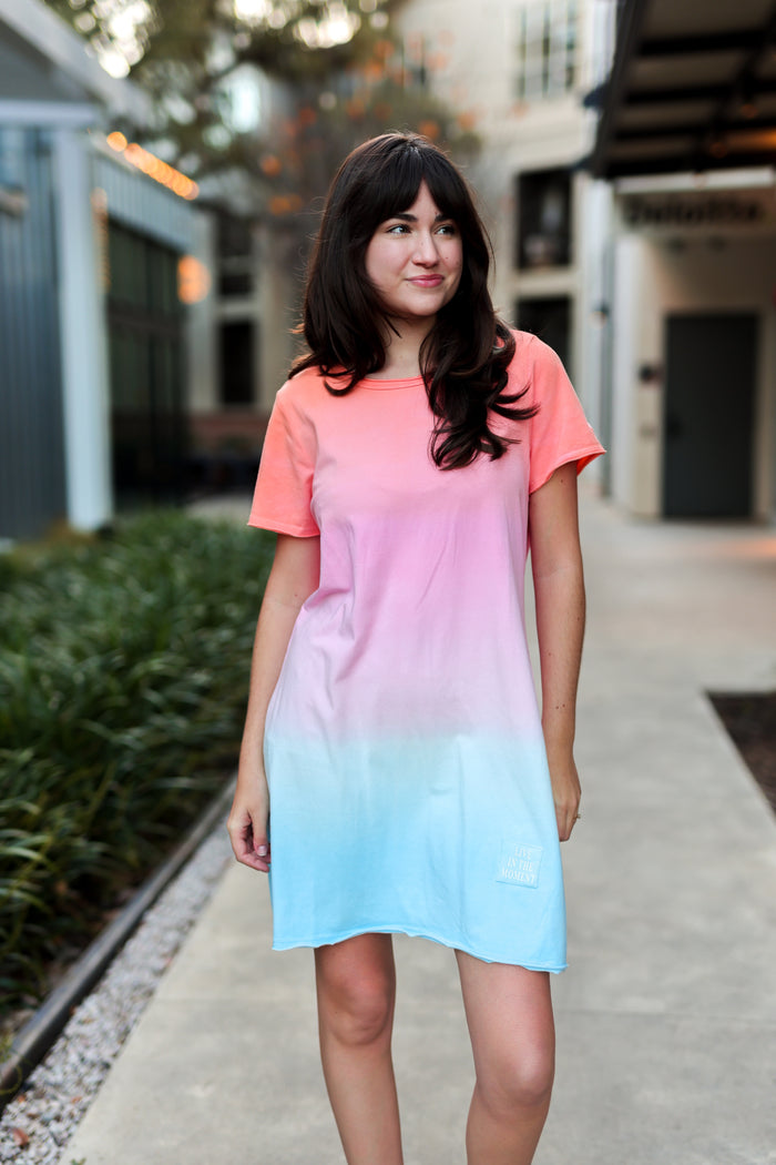 Short sleeve gradient dress in coral to blue ombre, featuring 'Live in the Moment' logo.