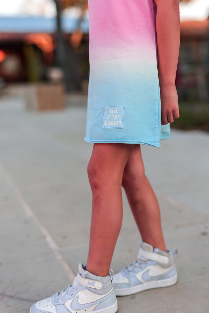 Kids' gradient dress in pink and blue, featuring 'Live in the Moment' embroidery and soft cotton fabric.