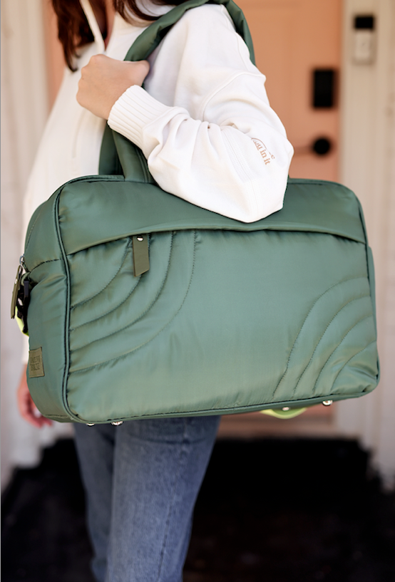 Stylish green quilted tote bag, ideal for everyday use and travel, featuring durable material and comfortable handles.