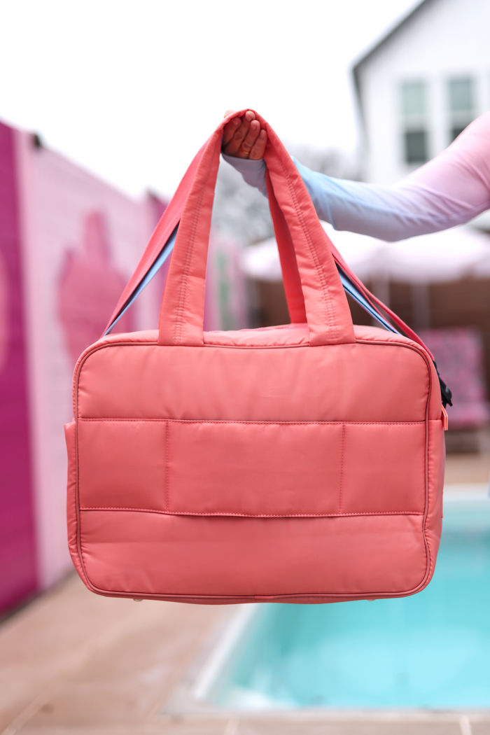 Pink padded tote bag with dual handles, ideal for daily use or travel, featuring a spacious interior.