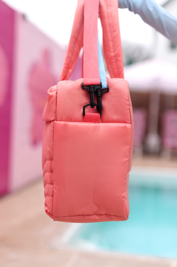 Peach quilted tote bag with adjustable straps and sturdy clips, perfect for stylish outings.