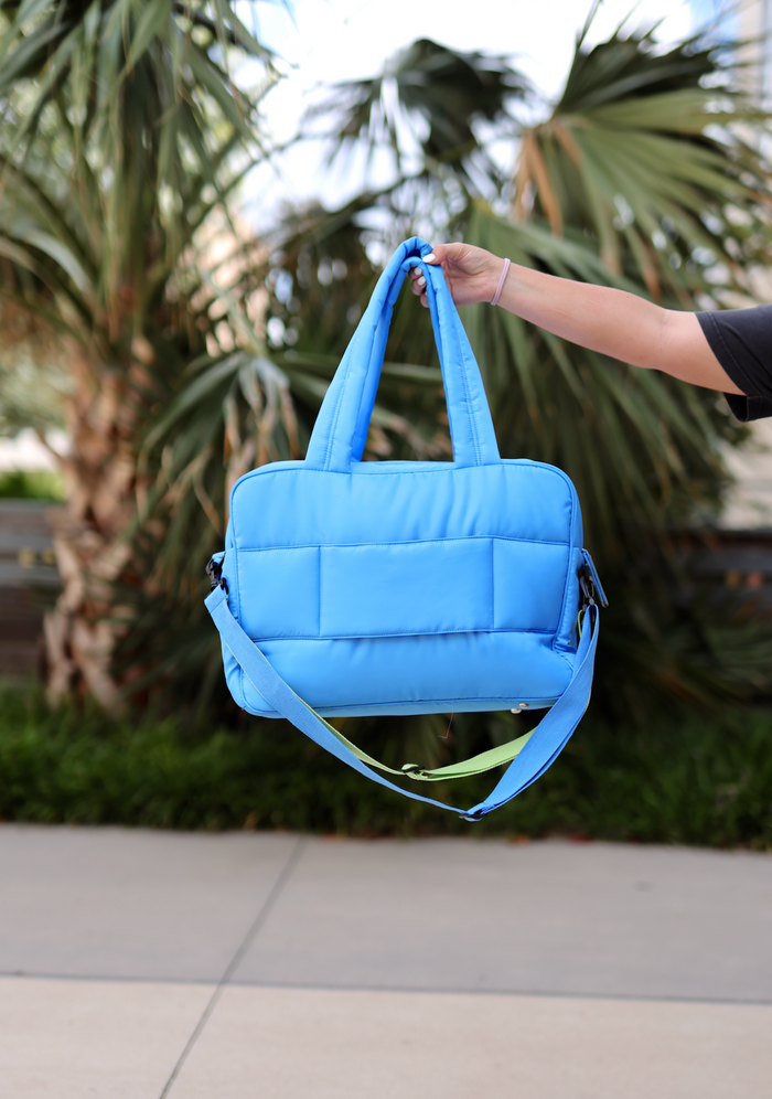 Stylish blue padded tote bag with adjustable strap, perfect for everyday use and casual outings.