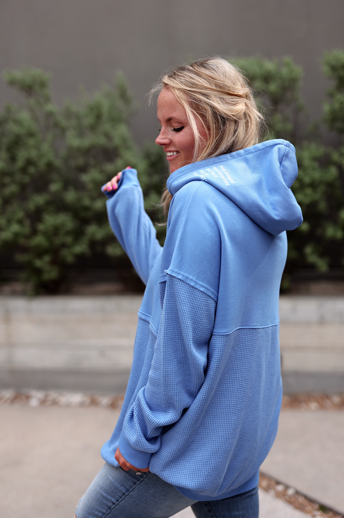 Relaxed-fit blue hoodie with textured fabric, featuring a spacious hood and stylish design.