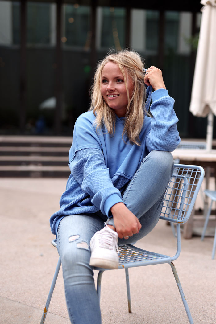 Casual blue oversized hoodie for women, comfortable fabric, styled with ripped jeans and white sneakers.
