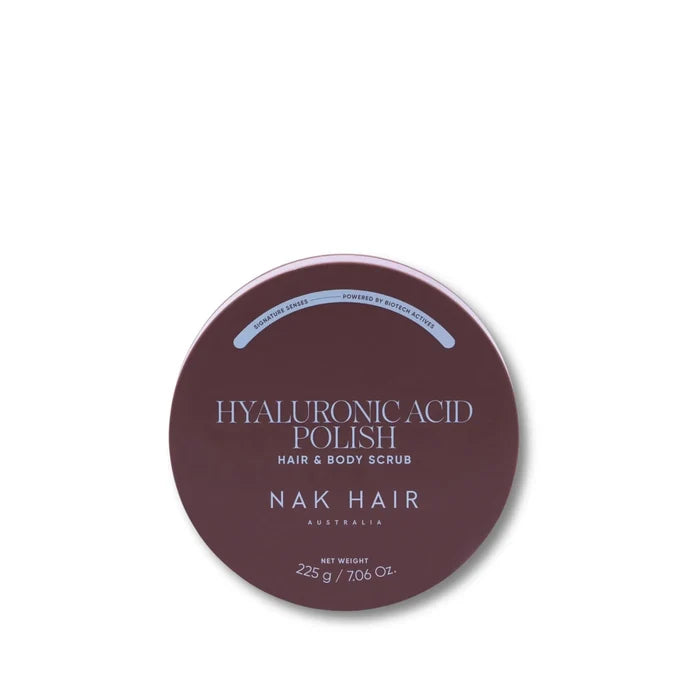 A round dark mauve-brown tin of NAK HAIR Hyaluronic Acid Polish Hair & Body Scrub on a clean white background.