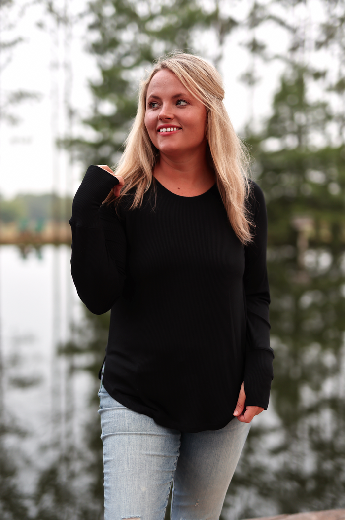 Black long-sleeve women's ribbed top, made of soft material, paired with light blue jeans.
