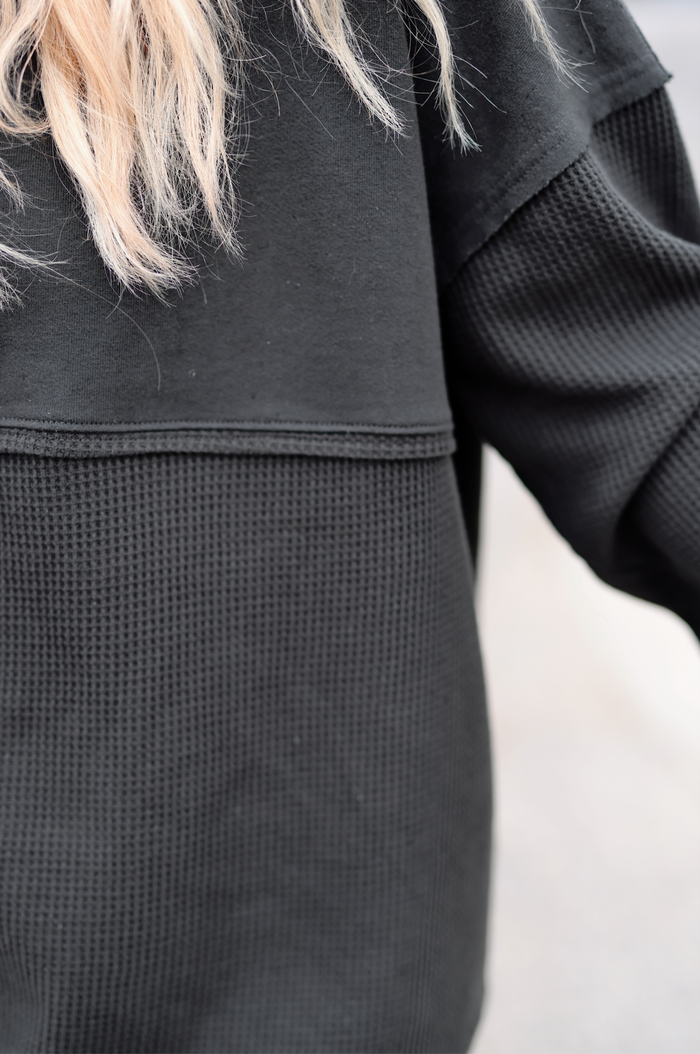 Black waffle knit pullover sweater with stylish detailing, perfect for casual wear.