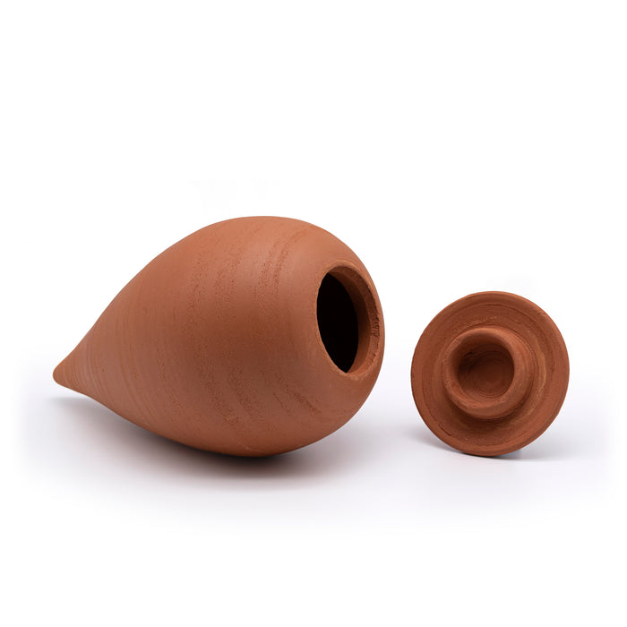 Small terracotta olla pot on it's side with the lid next to it.