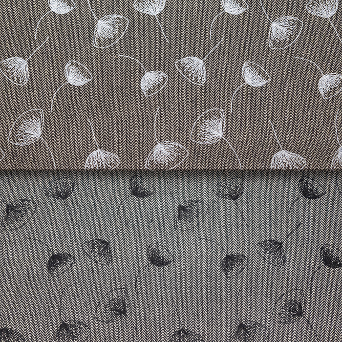 A close-up of a gray patterned fabric with a fine herringbone texture, featuring a white and black flower pattern.