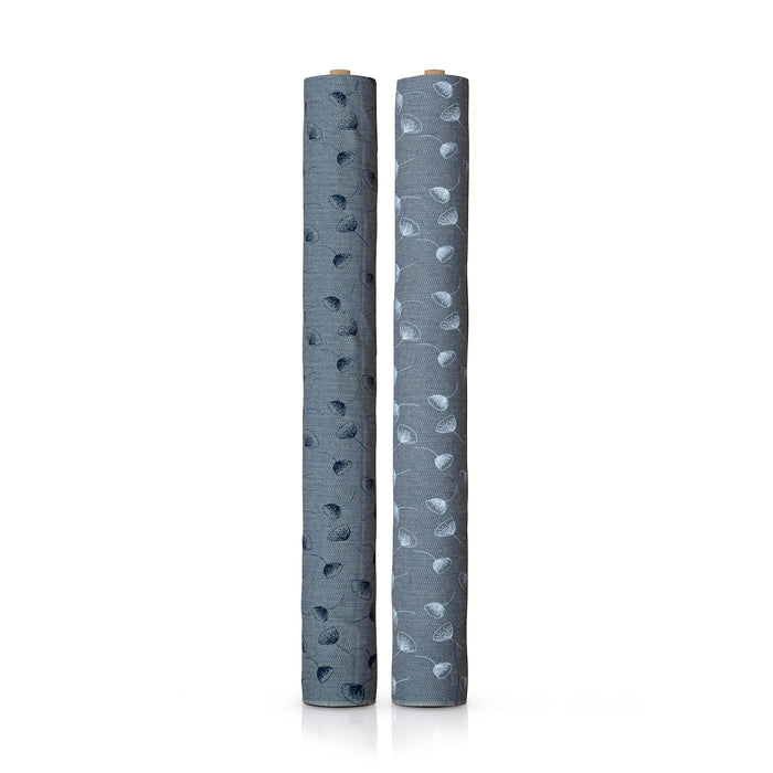 Two rolls of blue fabric standing up against a white background. Each roll has the same flower pattern, with one having blue flowers, and the other having white.