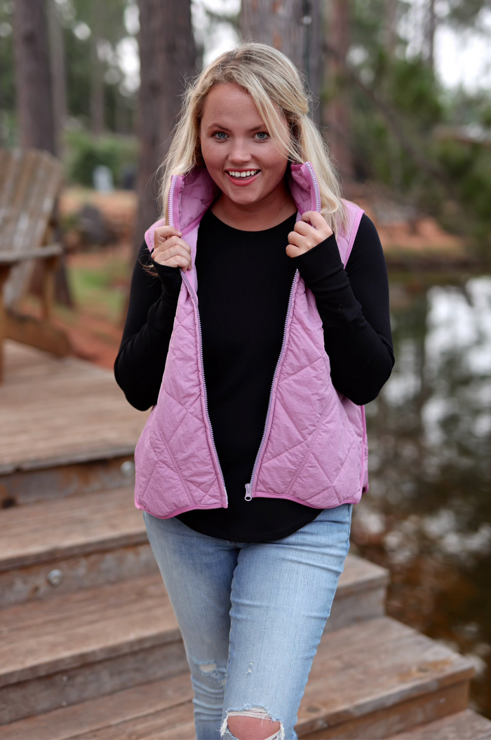 Light pink quilted vest paired with a black long-sleeve top and jeans, perfect for stylish warmth.