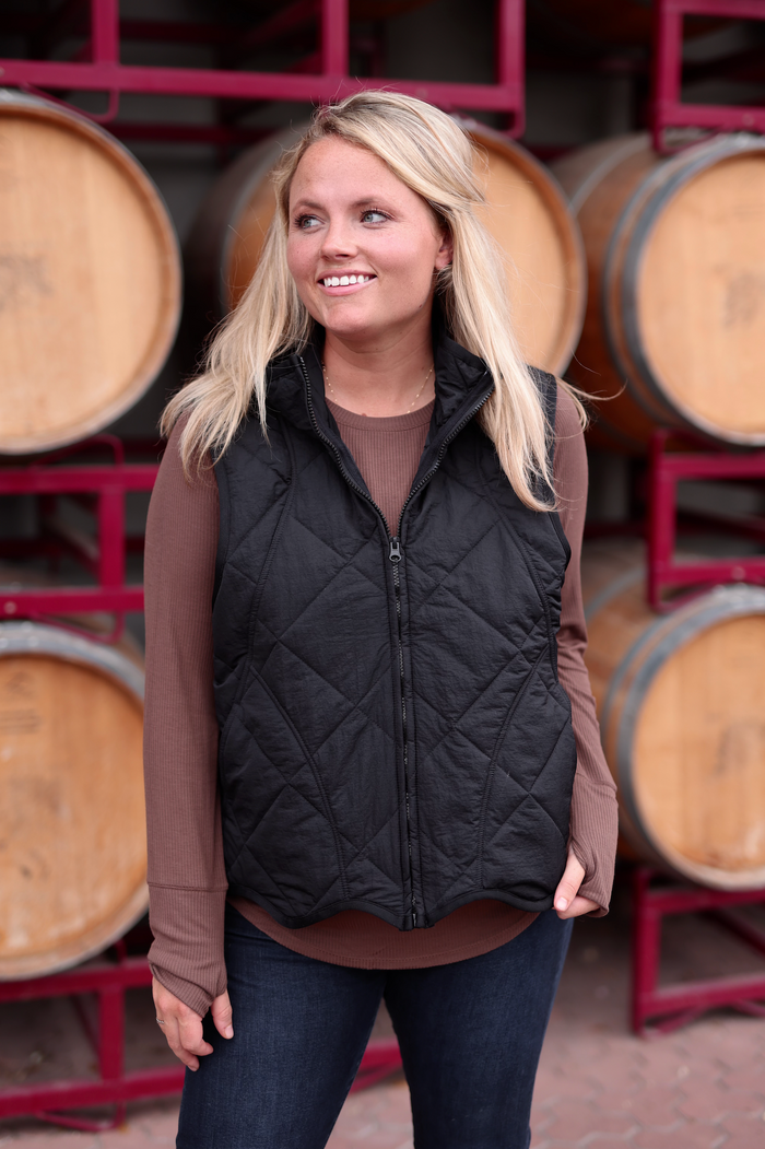 Women's black quilted vest in lightweight material, perfect for layering with a cozy sweater.