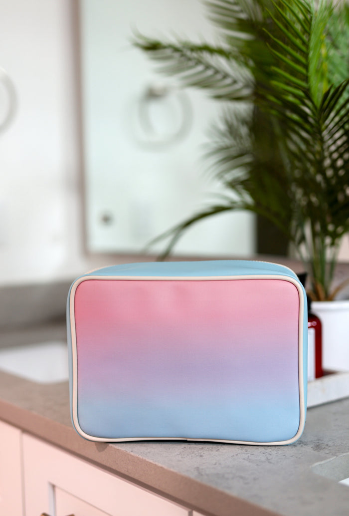 Pastel gradient makeup bag in pink and blue, made of durable material, perfect for cosmetics storage.