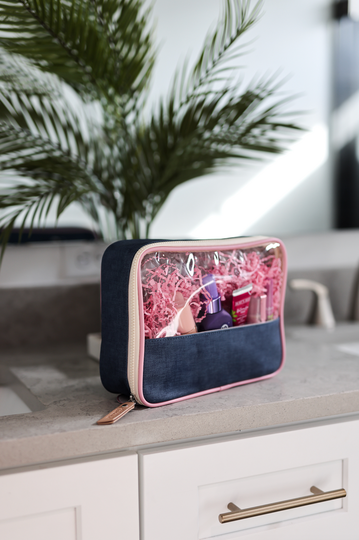 Navy blue toiletry bag with clear top, ideal for travel, featuring a stylish pink zipper.