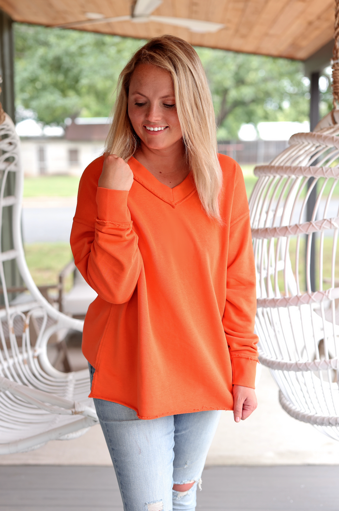 Women’s oversized V-neck sweatshirt in vibrant orange, made from soft material, perfect for casual wear.
