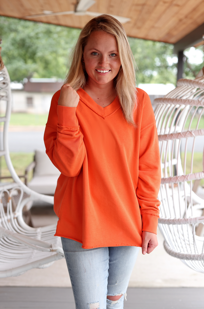 Women's oversized orange hoodie in soft material, featuring a V-neck and long sleeves, perfect for casual wear.