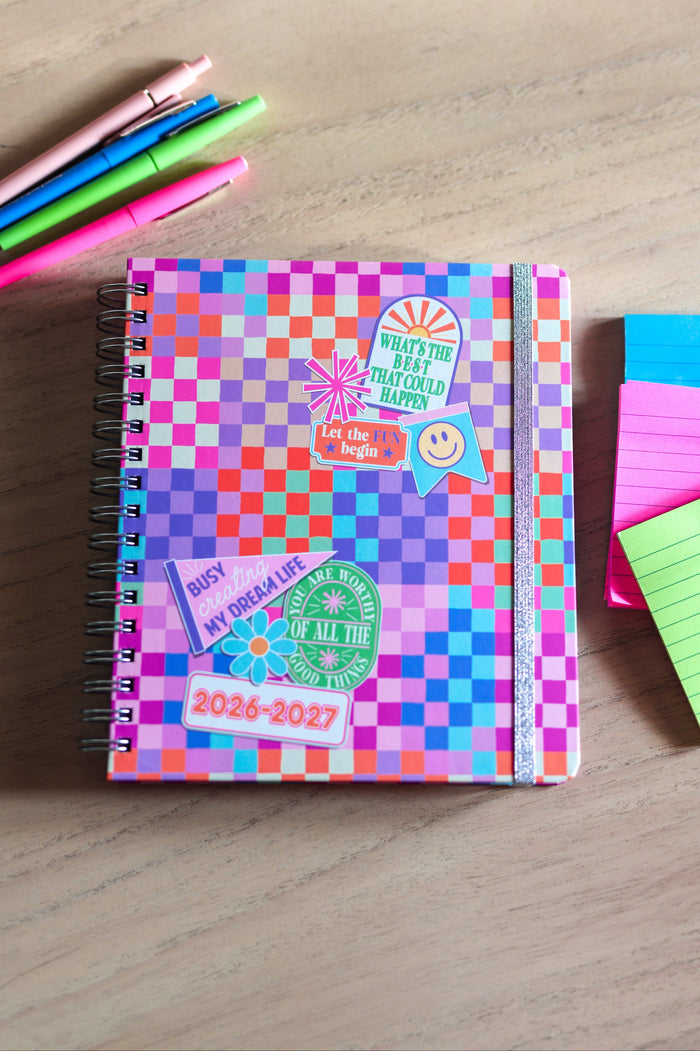 Colorful checkered planner with stationery items on a wooden surface
