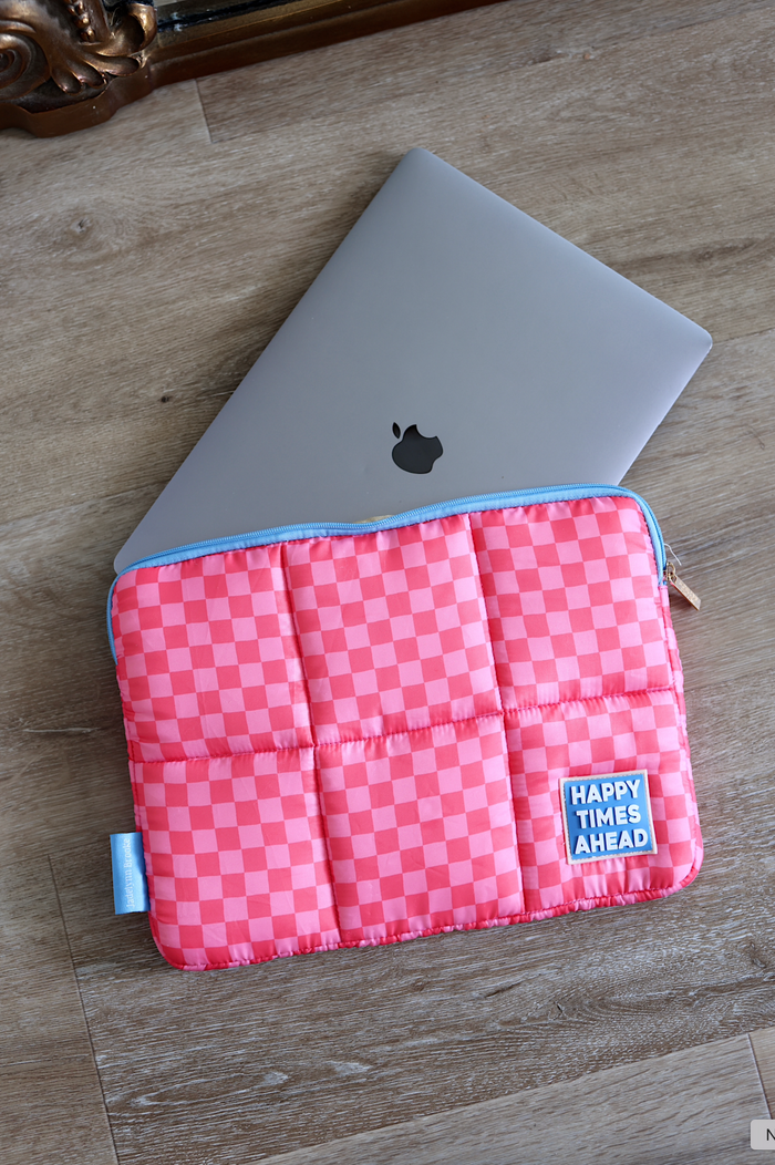 Pink checkered laptop sleeve with 'Happy Times Ahead' patch, padded for protection, stylish and colorful.