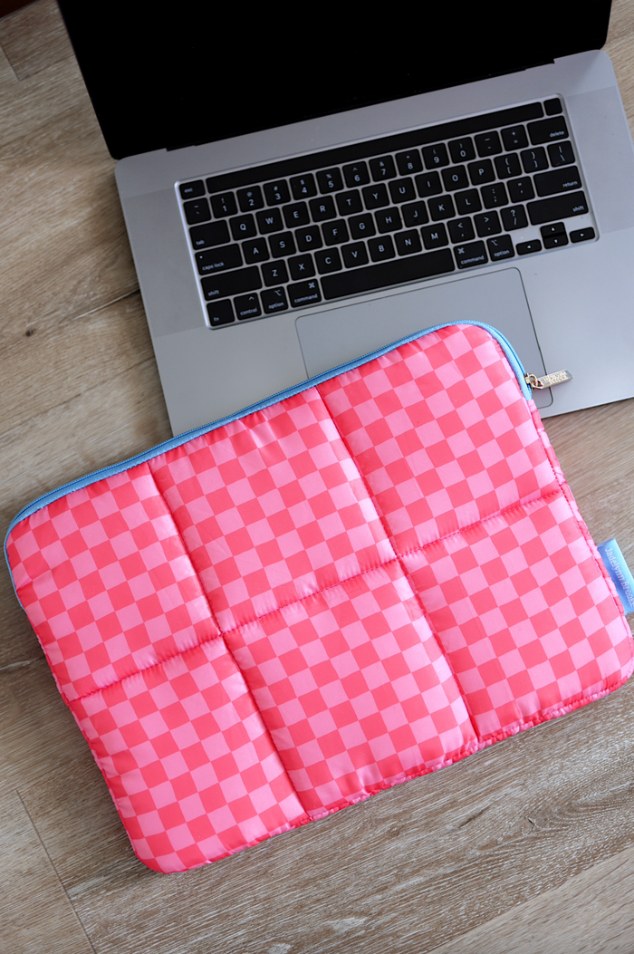Quilted pink checkered laptop sleeve with blue zipper, perfect for cushioning and protection.