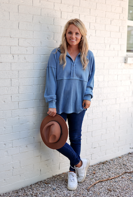 Light blue waffle knit pullover top with a quarter zipper, paired with dark jeans and a brown hat.