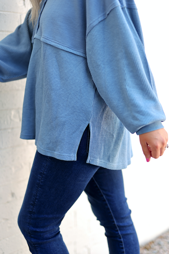 Cozy light blue oversized top with side slits, featuring a textured fabric, perfect for casual wear.