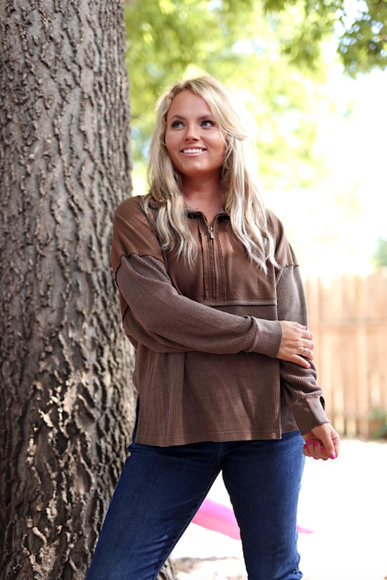 Brown zip-up hoodie made from soft fabric, perfect for casual outings, paired with jeans.