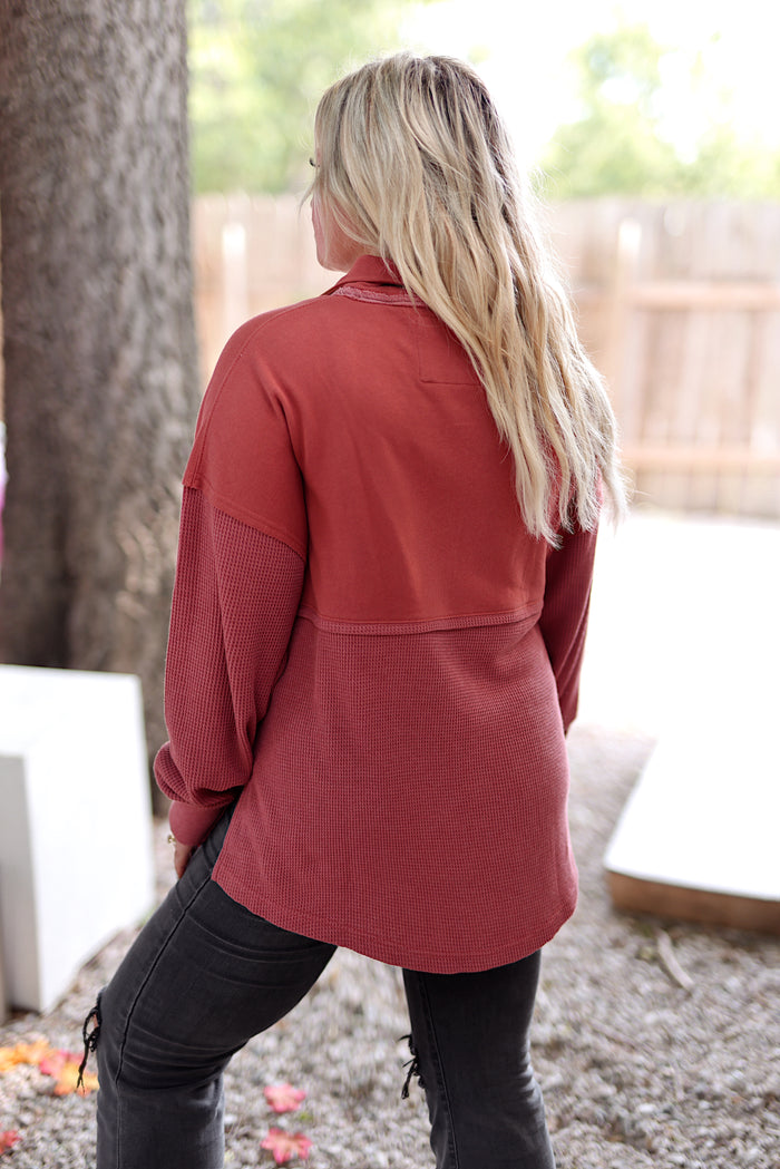 Back view of a cozy rust-colored long-sleeve top made from soft waffle knit material.