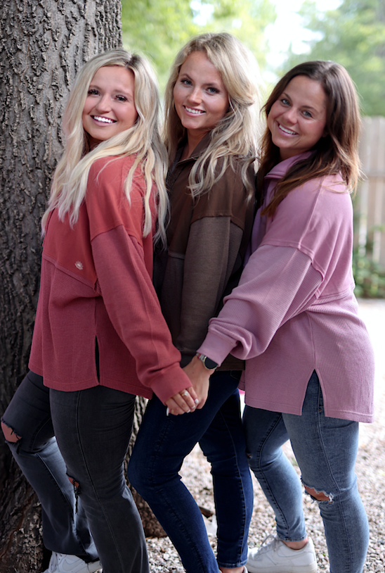 Three women wearing stylish oversized sweatshirts in rust, brown, and pink colors, perfect for casual outings.