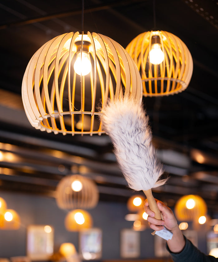 Wooden pendant lights with a lambswool duster in a blurred indoor setting