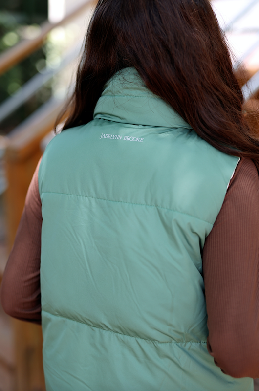 Women's jade green puffer vest by Jadelynn Brooke, featuring a high collar and lightweight design.