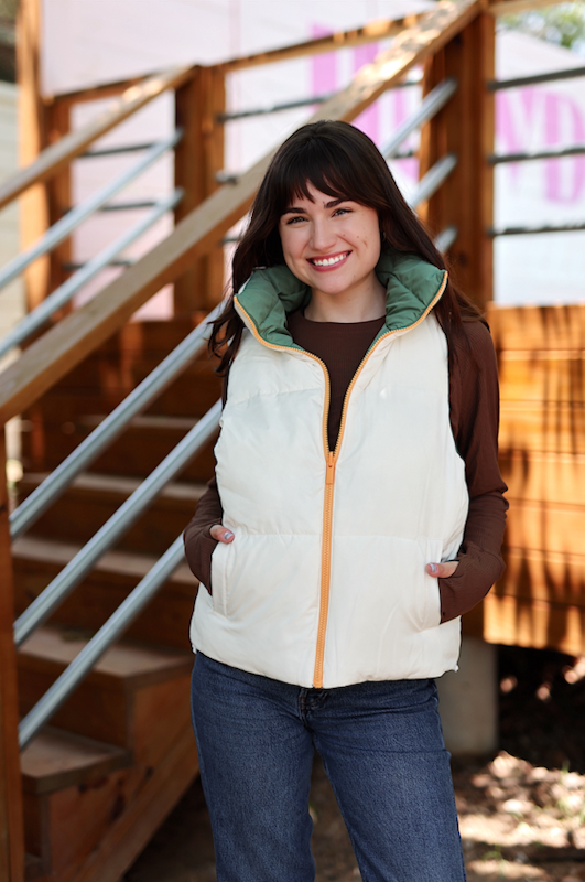 Women's padded vest in cream and green, featuring a zippered front and cozy pockets for warmth.