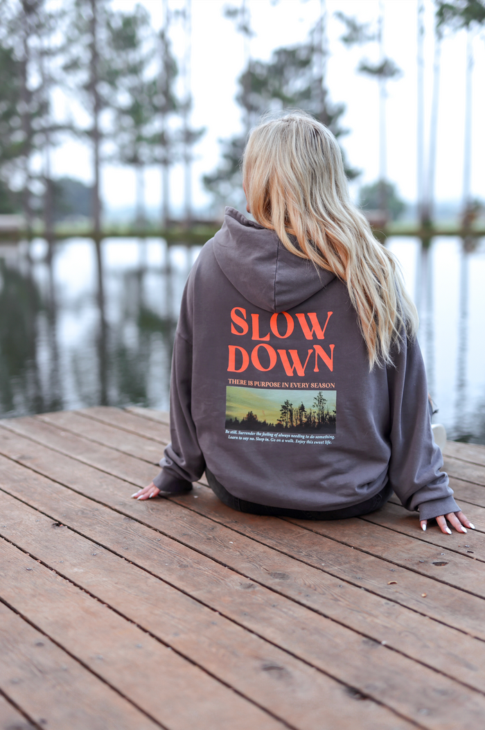 Cozy grey hoodie with 'SLOW DOWN' graphic, perfect for casual wear and relaxation.