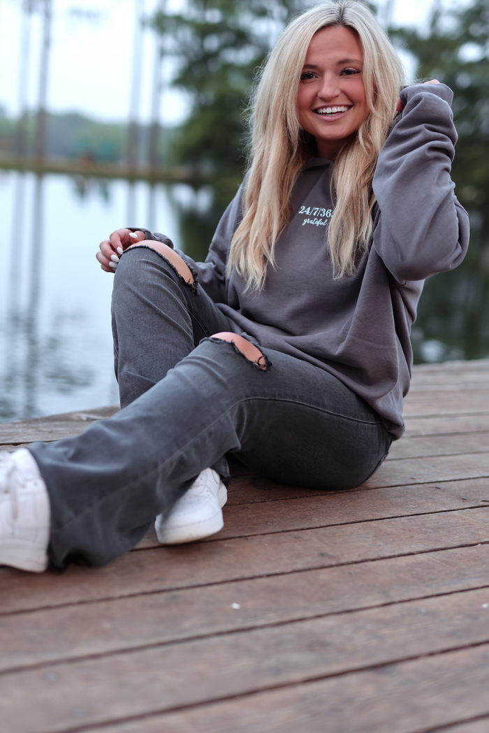 Cozy gray hoodie with 'grateful' print, paired with distressed gray jeans and white sneakers.