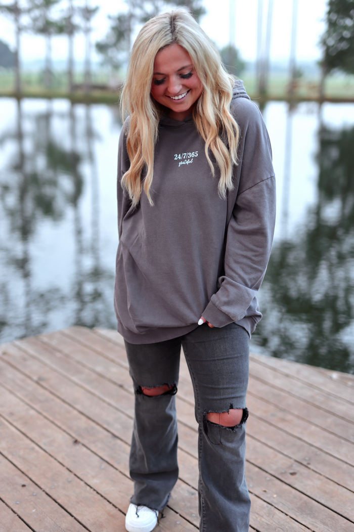 Cozy gray hoodie with '24/7/365 grateful' print, paired with distressed black jeans, perfect for casual wear.