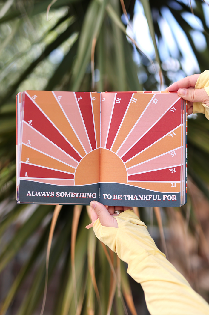 Open gratitude journal with sunburst design in warm colors, featuring 'Always Something to Be Thankful For'.