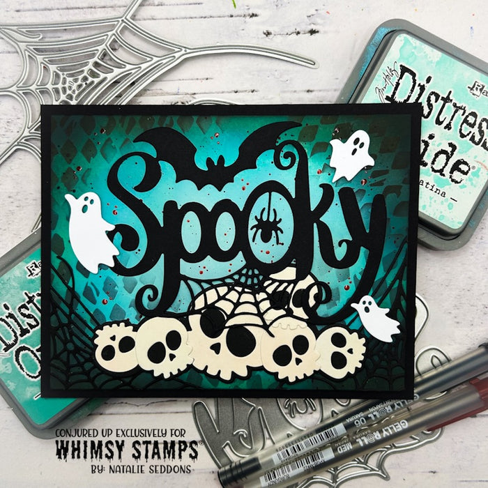 A handmade Halloween card featuring the word 'Spooky' in black script over a teal patterned background, with a bat, a spider, white ghosts, skulls, and spiderwebs.