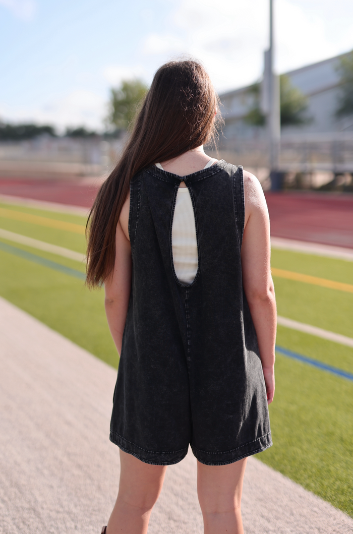 Black denim romper with a back cutout detail, perfect for casual summer outfits.