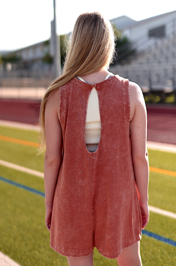 Rusty orange sleeveless romper with a stylish back cutout, perfect for casual summer outings.