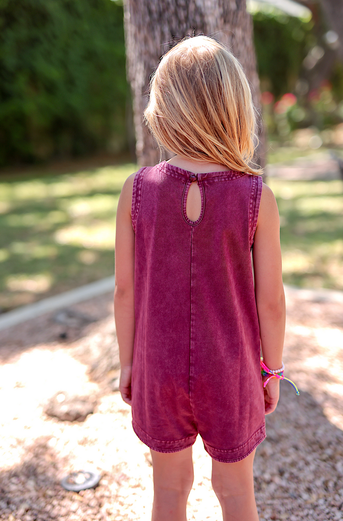 Back view of a girl's burgundy denim romper with keyhole detail and sleeveless design.