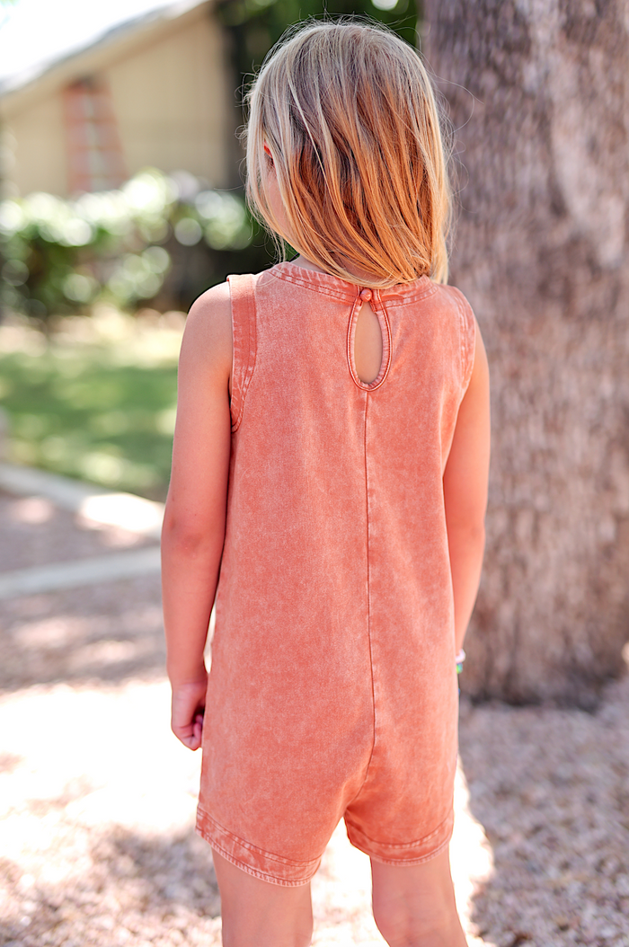 Girls' sleeveless romper in coral, soft cotton material with a back keyhole detail and casual fit.