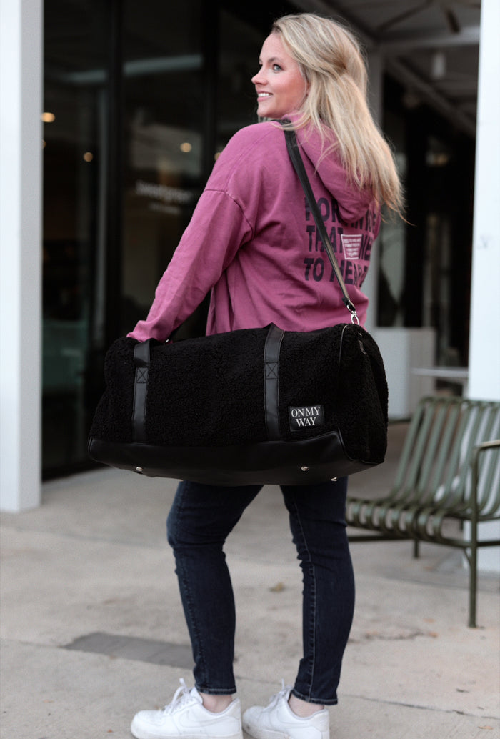 Black faux fur duffel bag with leather details, stylish and versatile for travel or gym use.