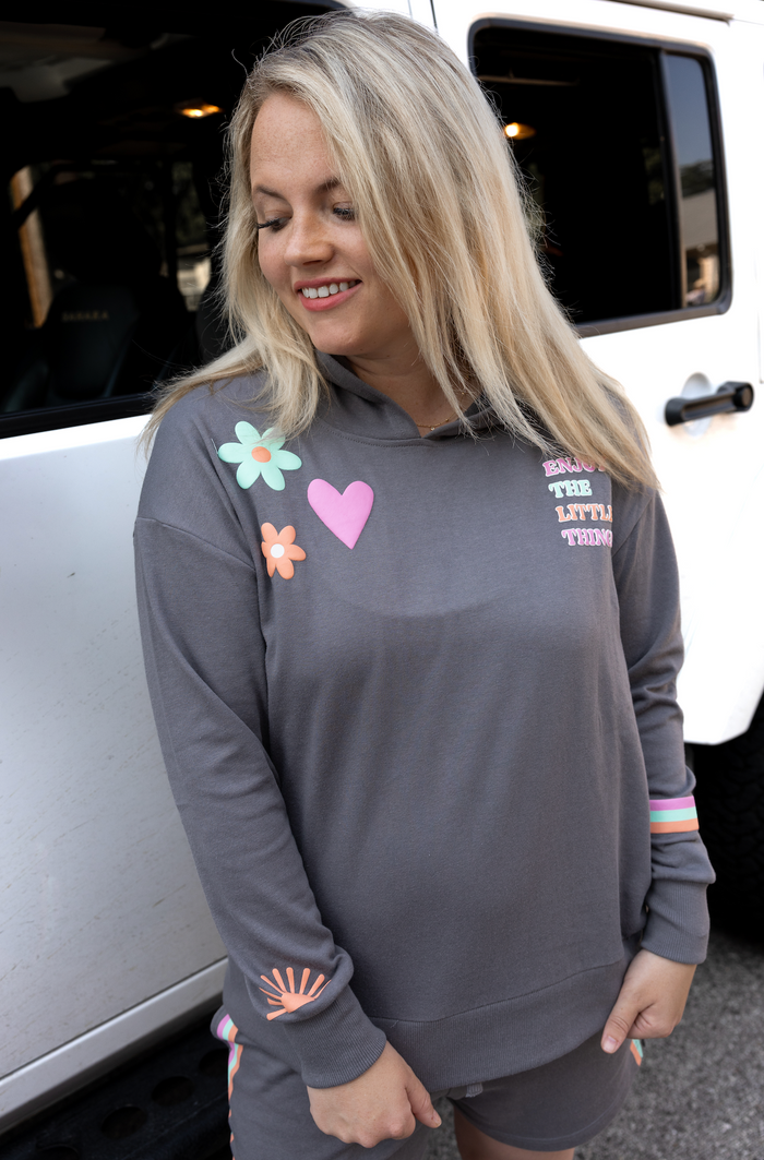 Light gray hoodie with colorful appliqués and text, made from soft fabric, perfect for casual wear.