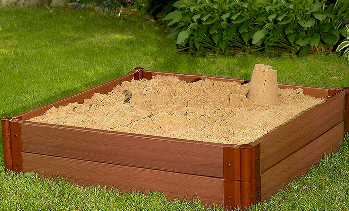 Tool-Free Classic Sienna Composite Square Sandbox Kit with deep sand and sandcastle on green grass in backyard
