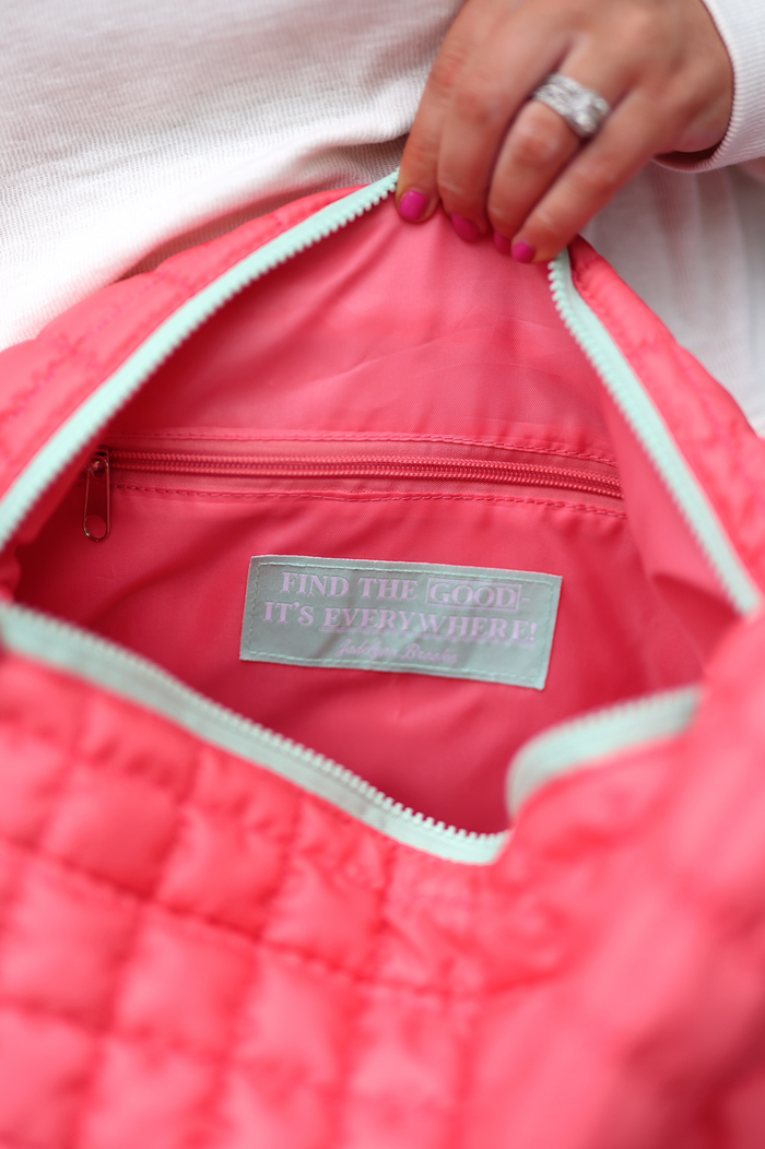 Interior of a quilted coral tote bag featuring a zipper pocket and a motivational label.