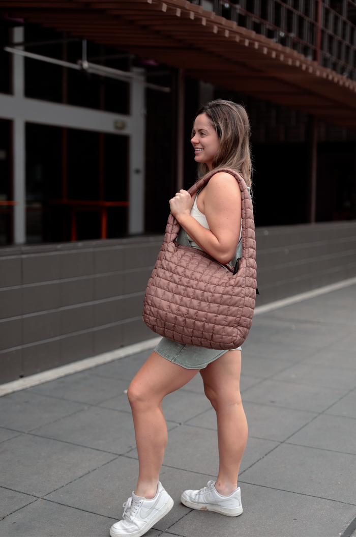 Brown quilted tote bag made from soft material, perfect for casual outings and daily use.