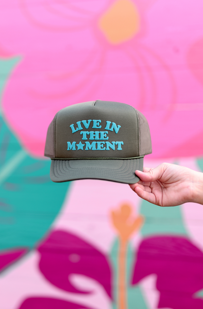 Olive green snapback hat with 'Live in the Moment' blue embroidery, perfect for casual outings.