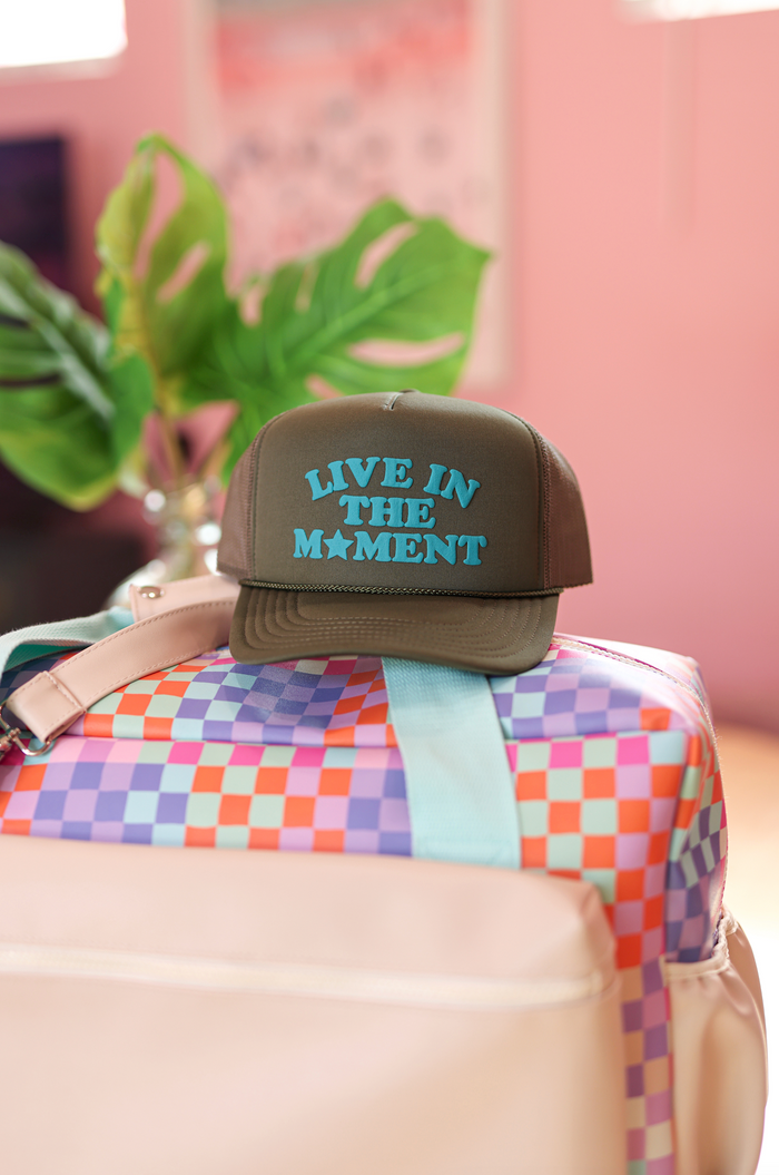 Brown trucker cap with 'Live in the Moment' design, perfect for casual outdoor style.