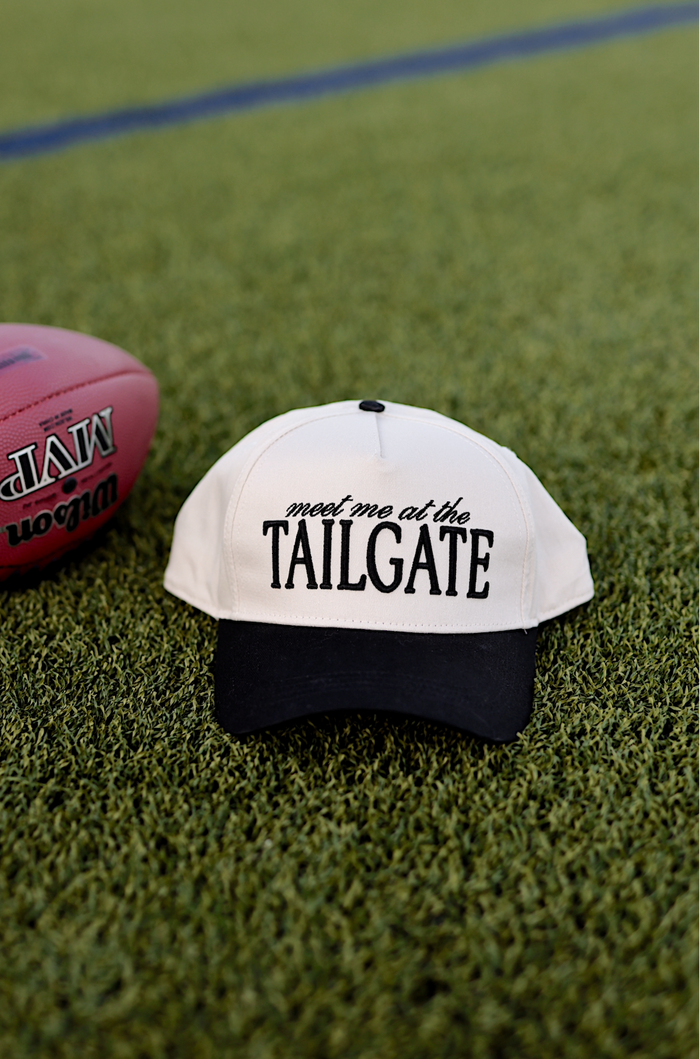 White and black baseball cap with 'meet me at the TAILGATE' text, perfect for sports events.
